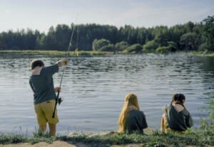 Family casting rods together at a mountain lake during a sunny fishing day