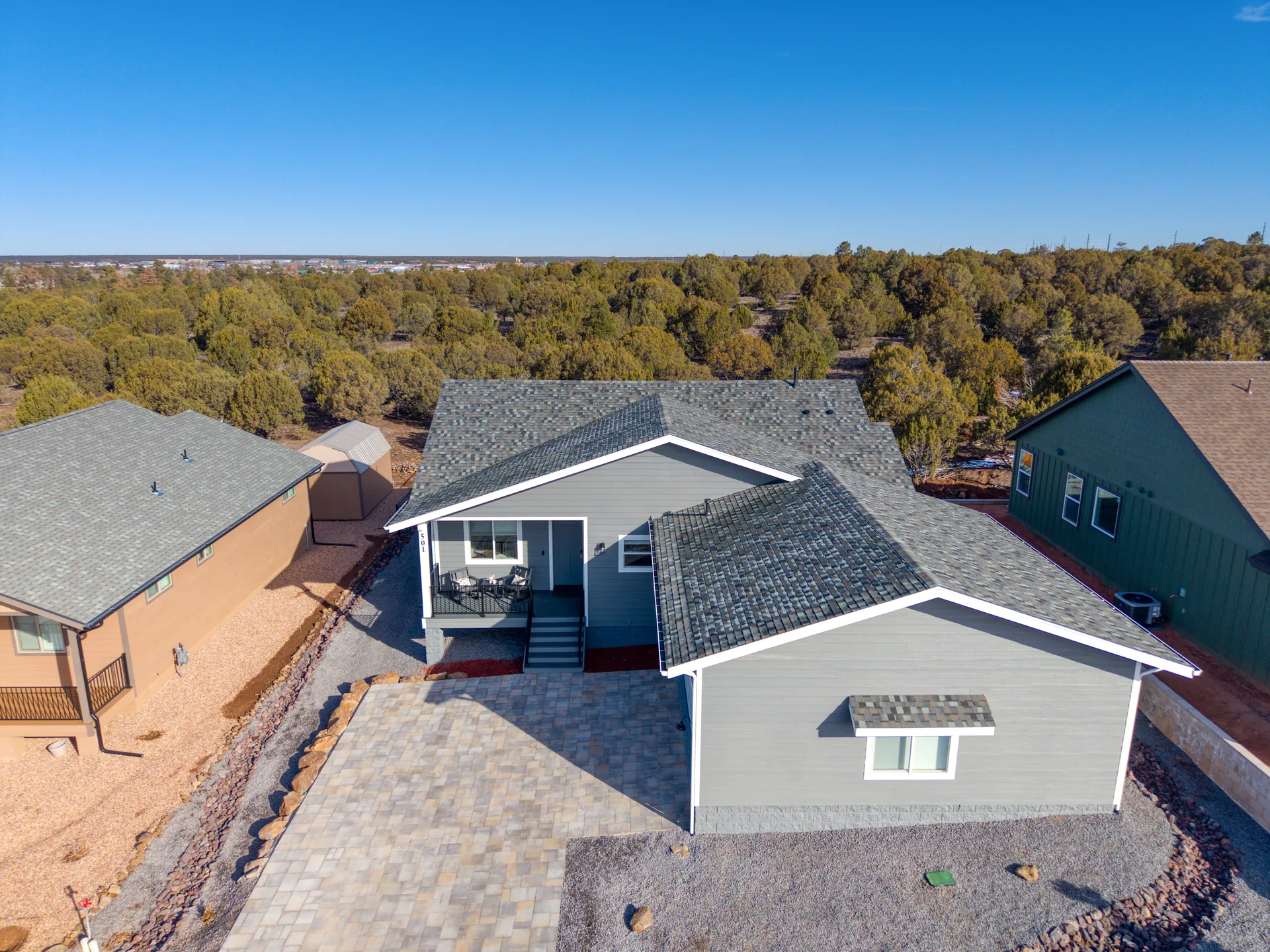 Aerial view of Bluff Retreat and its paver driveway surrounded by juniper forest in Show Low, Arizona