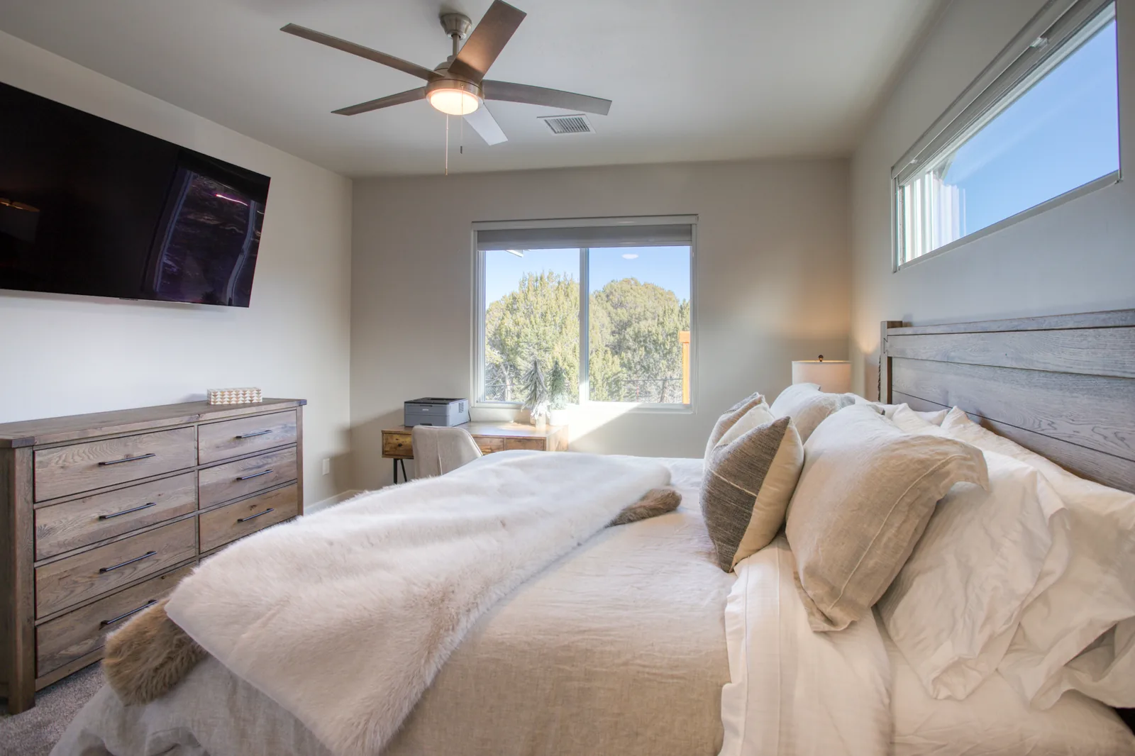 Primary bedroom with king bed, dresser, TV, and desk workspace