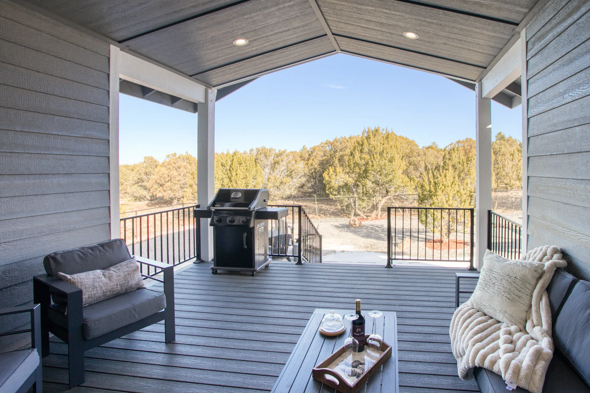 Covered back deck with grill and outdoor seating overlooking the trees
