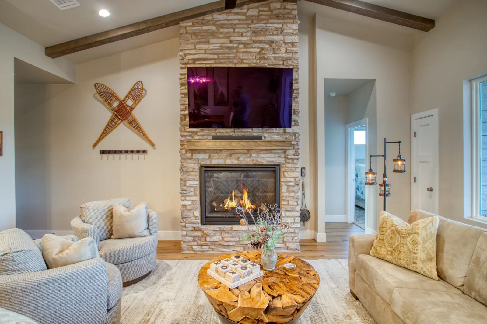 Living room with stone gas fireplace, mounted TV, and rustic wood coffee table